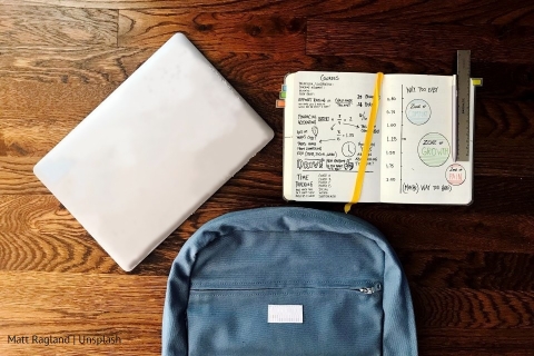 Plecak, laptop i zeszyt na biurku
